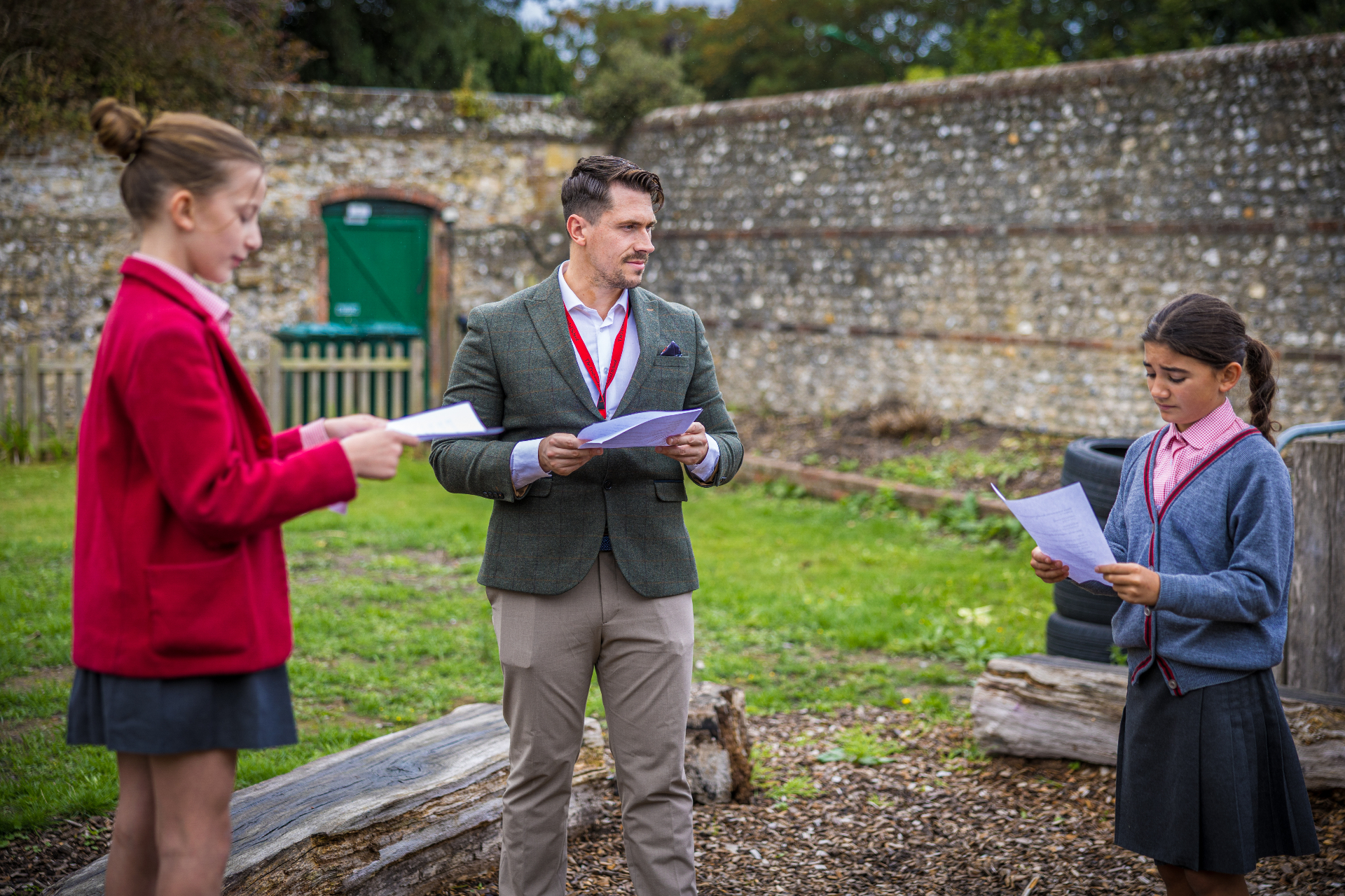 A teacher working closely with two pupils outdoors at The Prebendal School